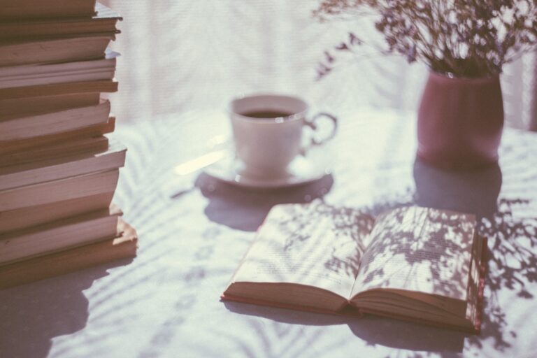Cup of coffee beside an open book on a table