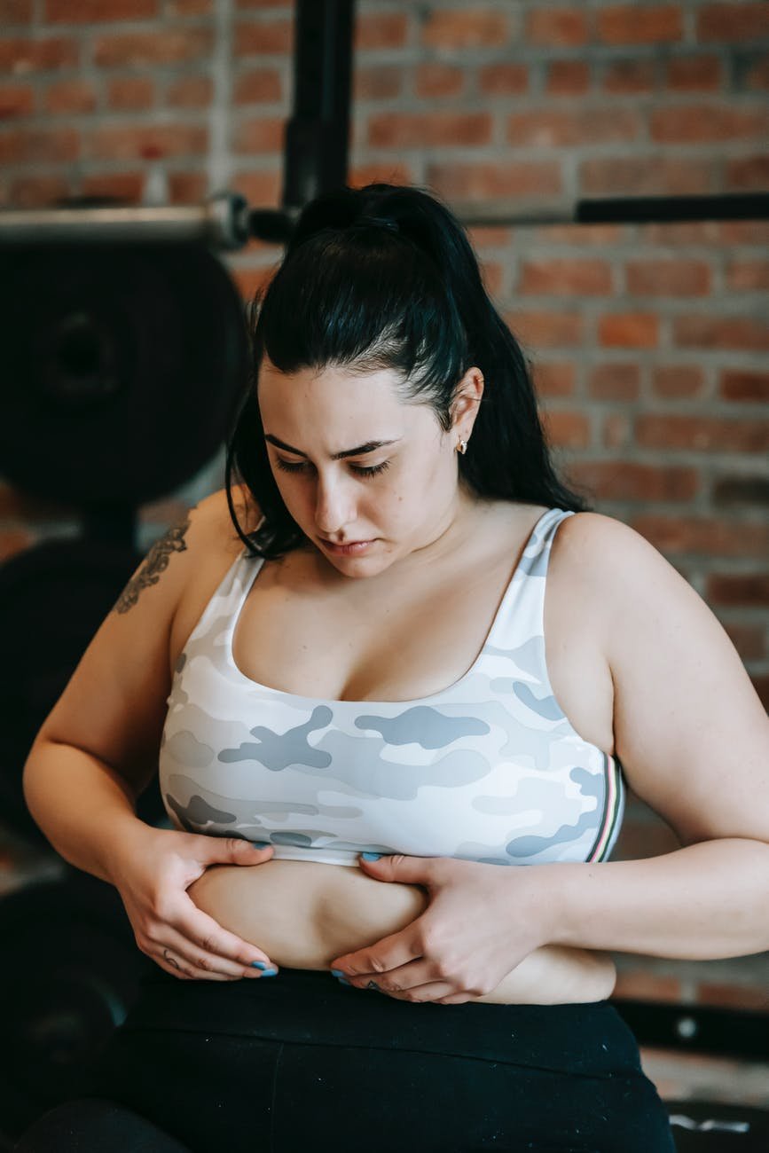 unhappy young overweight woman touching stomach before abs workout