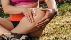 Woman holding her knee while experiencing pain and discomfort