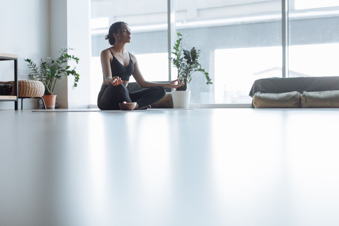Woman meditating in a softly lit room by a window, photographed by Thirdman on Pexels